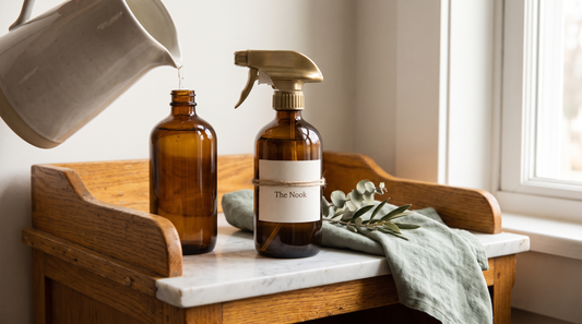 Refilling a reusable amber spray bottle at a natural home cleaning station to cut plastic waste