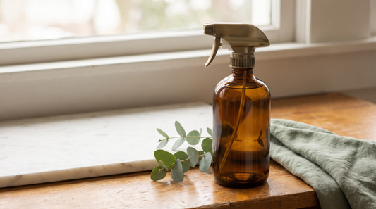 Amber refillable spray bottle on an oak counter, illustrating how much plastic a refill habit saves in a year
