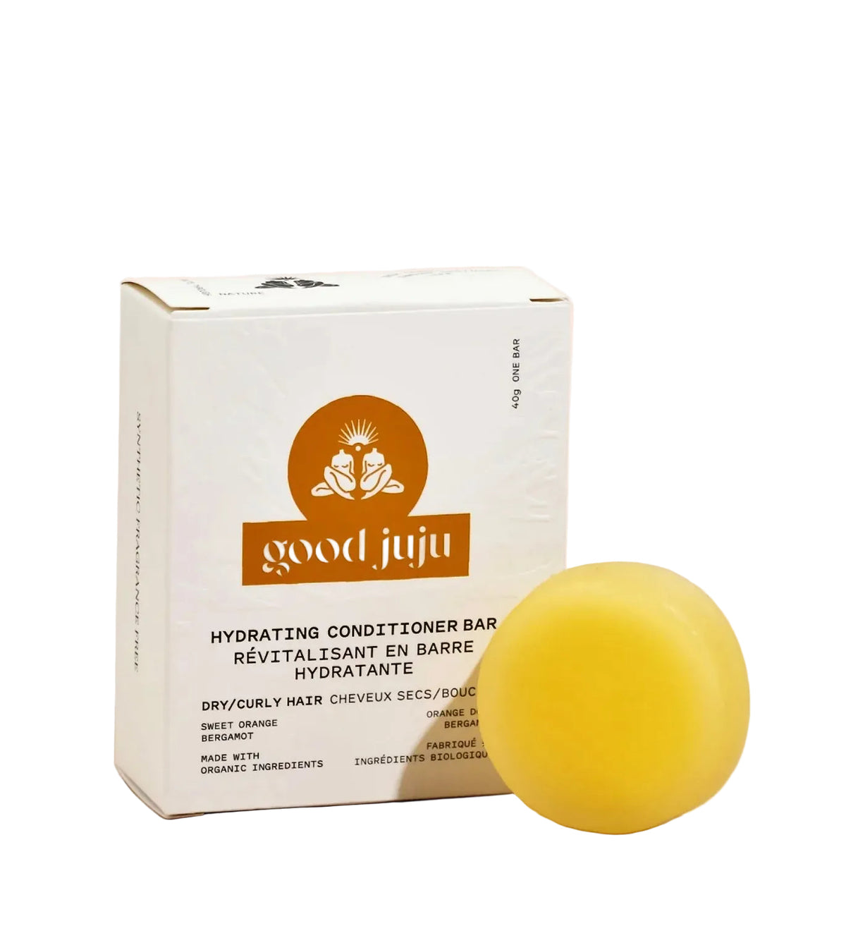 A yellow hydrating conditioner bar next to its white packaging box with an orange logo, labeled 'good juju' and 'Hydrating Conditioner Bar', on a solid pale pink background.